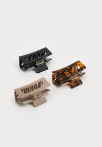 Three hair claws: one black, one tortoiseshell, and one beige. Each has a rectangular shape, toothed design, and metal hinge for grip.