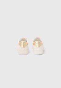 Pair of white sneakers with gold heel tabs embossed with "Michael Kors," viewed from the back on a plain white background.