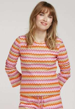 Haut en tricot à motif zigzag multicolore en rose, orange et crème, avec des manches longues et un col rond. Finition en tissu texturé.