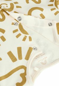Cotton baby bodysuit in cream with gold abstract patterns, featuring snap closures at the bottom and a soft, textured finish.