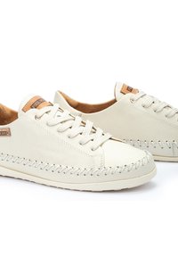 Zapatillas deportivas blancas de cuero con punta redonda, cierre de cordones y detalles cosidos a lo largo de la suela. Plantilla de cuero natural, parche con el logo en la lengüeta.