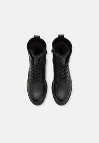 Černé kožené kotníkové boty s hladkým povrchem, šněrováním v přední části a měkkou kožíškovou podšívkou, s bočním zipem.