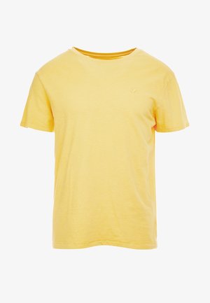 Yksinkertainen keltainen lyhythihainen puuvillainen T-paita, jossa pyöreä kaula-aukko ja pieni kirjailtu logo vasemmassa rinnassa.