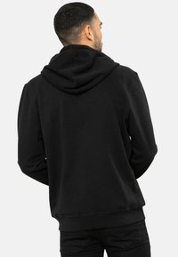 Sort hættetrøje med en blød tekstur, der har en stor hætte bagpå, elastiske manchetter og en elastisk kant. Enkel design uden synlige logoer eller mønstre.