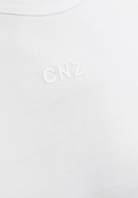 Vit bomulls t-shirt med en texturerad "CNZ"-logotyp i matchande vitt. Rund halsringning och jämn, slät tygliknande struktur.