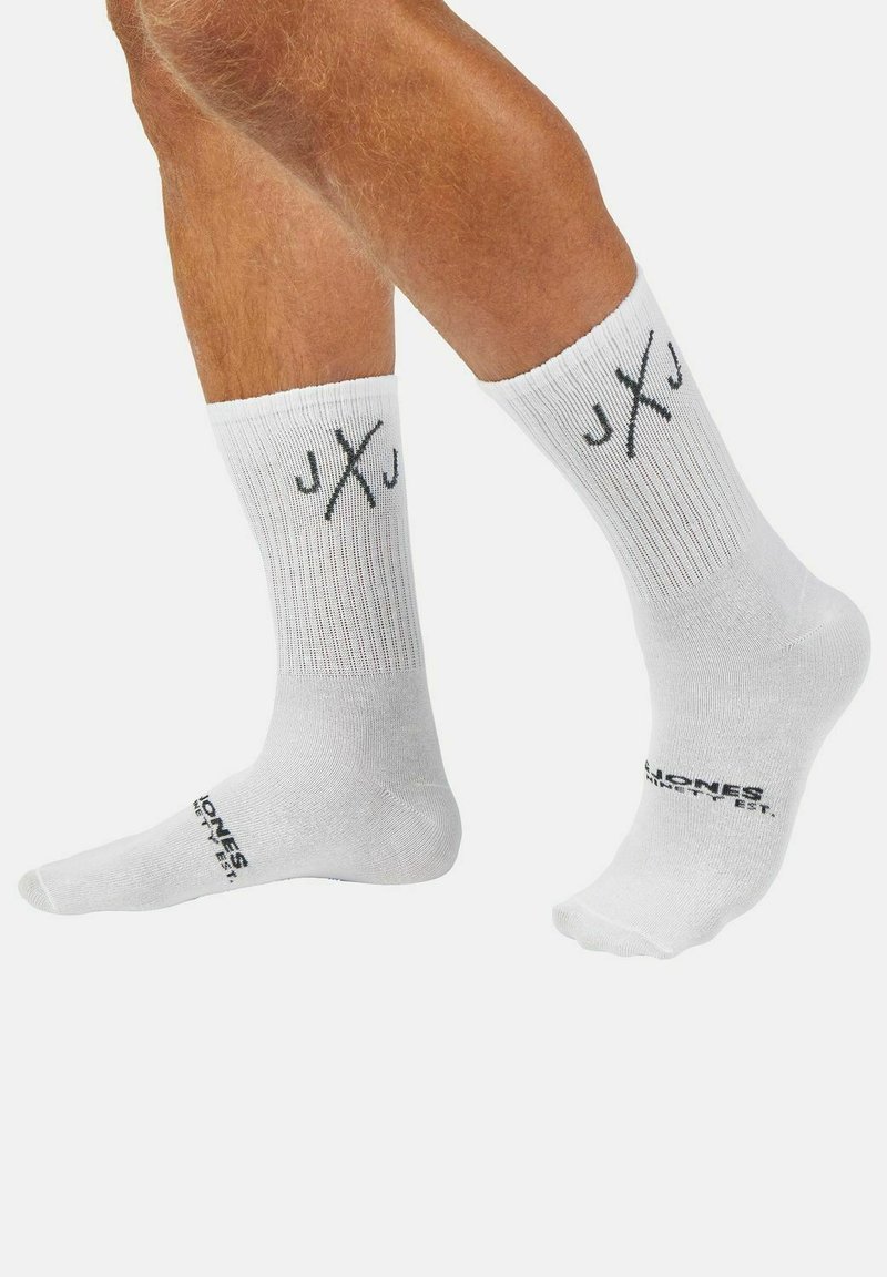 Witte katoenen crew sokken met ribbeltextuur, voorzien van het zwarte "JXJ" logo op de boord en "Jones" merknaam op de zijkant.