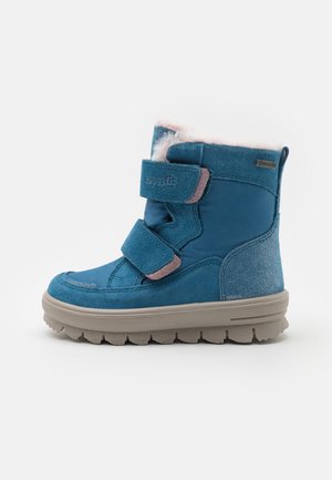 Bottes d'hiver bleues avec une doublure en fourrure douce et rose, deux bandes velcro, un matériau textile et en daim lisse, et une semelle en caoutchouc texturée.