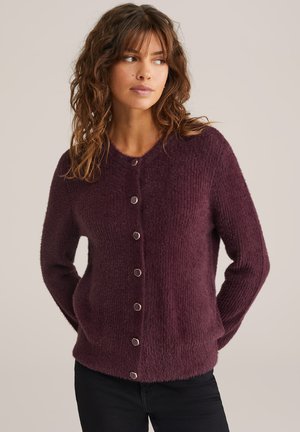 Cardigan en tricot bordeaux avec une finition douce et texturée, doté d'un col rond et de boutons hexagonaux métalliques sur le devant.