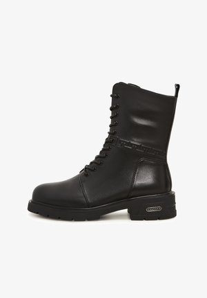 Czarne skórzane botki za kostkę na sznurówki, z zaokrąglonym noskiem, teksturowanymi akcentami i solidną podeszwą, z wyraźnym detalem metalowym po boku.