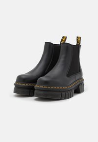 Zwarte leren Chelsea boots met elastische zijkanten, gele stiksels, een dikke platformzool en trekhaakjes aan de achterkant.