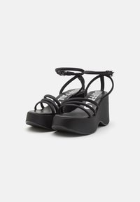 Black platform sandals with multiple narrow straps and an ankle buckle. Made from smooth material, featuring a contoured sole for added height.