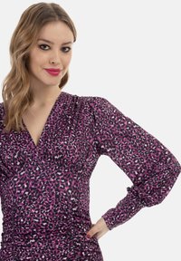 Lila Leopardenmuster Kleid mit langen Puffärmeln, gerafftem Taillenbund und tiefem V-Ausschnitt. Weicher, leichter Stoff.