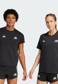 Svarta atletiska t-shirts och shorts tillverkade av andningsbart material, med vita logotyper och kontrasterande ränder för en sportig look.