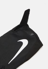 Black athletic glove featuring a prominent white Nike logo, smooth fabric, reinforced stitching, and a Velcro loop for easy wear.