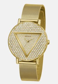 Rund guldur med netbånd, dækket af små krystaller. Har et trekantet design i midten med sort mærkelogo og gyldne visere.