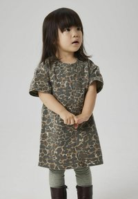 Robe à manches courtes en imprimé camouflage dans des tons terreux avec une coupe droite. Assortie à des collants vert clair et des bottes marron foncé.