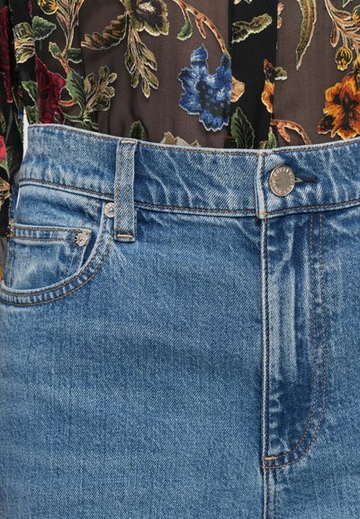 Denim jeans with a high waist, light blue color, contrasting orange stitching, and silver hardware on the button and rivets.