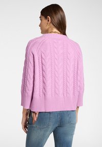 Sweter warkoczowy w delikatnym różowym kolorze, z prążkowanym dołem i rękawami o długości do łokcia. Teksturowany wzór na plecach dodaje wizualnego uroku.