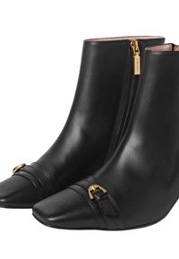 Zwarte leren enkellaarsjes met een spitse neus, ritssluiting, gouden hardwareaccenten en horizontale banddetails bij de enkel.