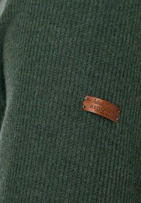Dunkelgrüner Strickpullover mit gerippter Textur, ausgestattet mit einem braunen Lederetikett, auf dem "Authentic Clothing REDMOND" eingraviert ist.