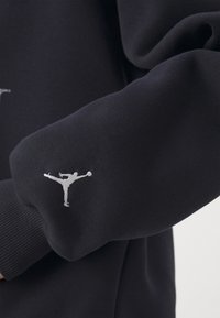 Sudadera navy con puños acanalados y un logo Jumpman bordado en blanco en la manga izquierda. Tejido suave y texturizado.