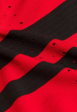 Rot-schwarz gestreifter Strickstoff mit mehreren kleinen Löchern, die über die Oberfläche verteilt sind.