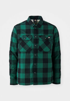 Green and black checkered flannel shirt with a button-down collar, two chest pockets, and black metal snap closures. Soft texture.