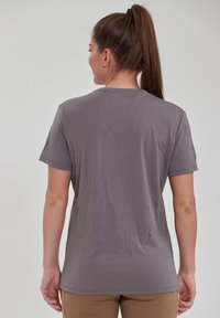 Grå tætsiddende t-shirt med korte ærmer, glat tekstur og rund hals, vist fra ryggen med minimale rynker.