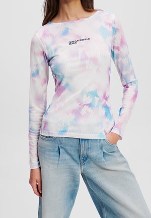 Femme portant un t-shirt manches longues tie-dye pastel avec le texte « KARL LAGERFELD JEANS » et un jean taille haute bleu clair.