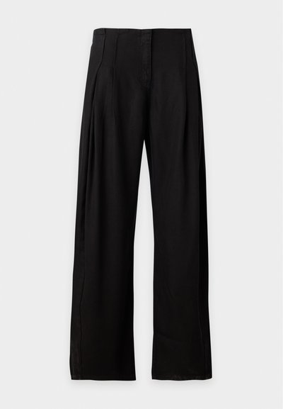 Pantalon noir taille haute à jambes larges avec poches latérales, fermeture éclair devant et finition en tissu lisse, présenté sur fond blanc.