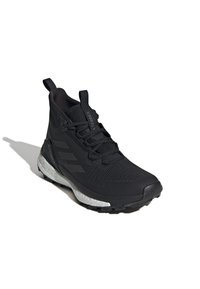 Black hiking shoe with a textured upper, reinforced toe, and a white midsole. Features a high ankle and durable rubber outsole.