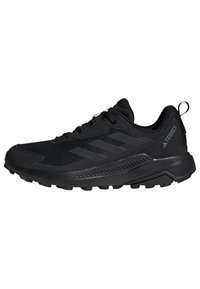 Chaussure de sport noire avec upper en maille et semelle en caoutchouc. Dotée d'un design texturé et d'une languette au talon. Conçue pour les activités de plein air.