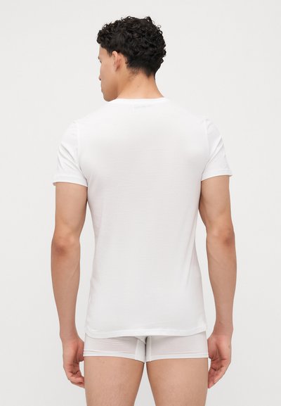 Tricou alb cu mânecă scurtă, confecționat dintr-un material moale, cu guler rotund și un design ajustat, prezentat din spate. Textură netedă.