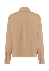 Tan long-sleeve shirt with a collared neck, back pleat detail, and gold button accents on the cuffs. Smooth, lightweight fabric texture.