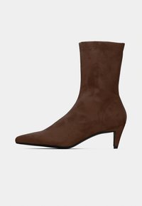 Καφέ μπότες αστραγάλου από καστόρι με μυτερό δάχτυλο και χαμηλό, κωνικό τακούνι. Ομαλή υφή με ελάχιστες ραφές.