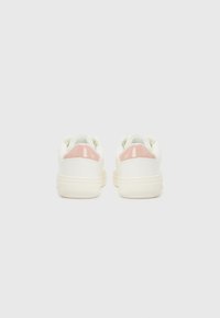 Sneakers bianchi con una finitura liscia, caratterizzate da un accento rosa lucido sul tallone, design a punta tonda e suola testurizzata.