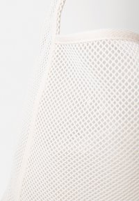 Sac tote en maille de couleur crème avec un motif en diamant, présentant un tissu solide et un bord supérieur doux, conçu pour la durabilité et la respirabilité.