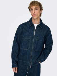 Denimjakke med glidelås, to frontlommer, kontrastsøm og klassisk krage. Mørkeblå farge, avslappet passform.