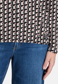 Koszulka z długim rękawem z czarno-białym różowym wzorem żaglówki na jasnym tle; materiał bawełniany z elastycznym dołem.