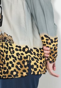 Langærmet skjorte i letvægtstof, med en gradient fra grå til gul og sort leopardmønster samt sidespalter.