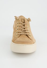 Baskets en suède beige avec œillets dorés et lacets assortis, dotées d'un bout rond et d'une semelle en caoutchouc blanc texturé.