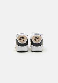 Tenisky Nike Air s černobílým designem. Obsahují texturované materiály, polstrovaný límec, logo na patě a kontrastní béžové akcenty.