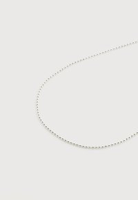 Λεπτό ασημένιο κολιέ με αλυσιδίτσα σε σχήμα μεταλλικών μπαλών, τοποθετημένο σε χαλαρό βρόχο πάνω σε απλό λευκό φόντο.