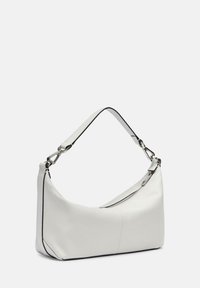 Sac à épaule en cuir blanc avec une forme arrondie, des contours noirs et une fermeture éclair en argent, doté d'une courte anse pour un transport facile.