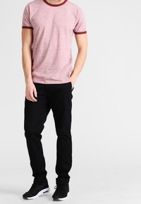 Červené melírované tričko s vínovým límcem a manžetami, v kombinaci s černými kalhotami a černými teniskami. Jednoduchý, ležérní outfit.