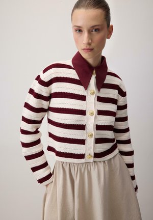 Red and white striped knit sweater with a burgundy collar and gold buttons, paired with a cream-colored flared skirt. Smooth texture.