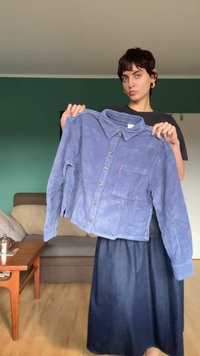 Blue corduroy shirt with a collared neckline, button-front, and a chest pocket. Features vertical ribbed texture and golden buttons.