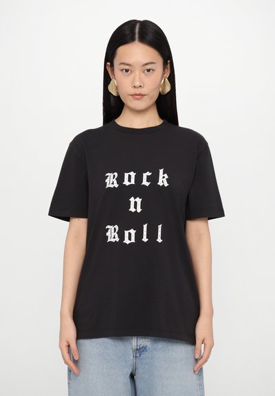 Black cotton t-shirt featuring large white gothic lettering "Rock n Roll" on the front. Short sleeves, relaxed fit, and crew neckline.