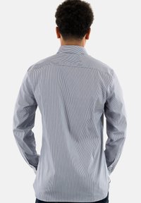 Camicia a maniche lunghe a righe in azzurro chiaro e bianco, con colletto classico e polsini con bottone, tessuto morbido, vestibilità aderente e dettaglio sulla schiena.