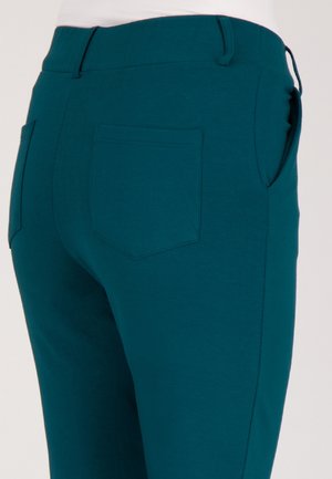 Teal stretchbroek met een gladde textuur, voorzien van een achterzak en een elastische tailleband voor comfort en flexibiliteit.